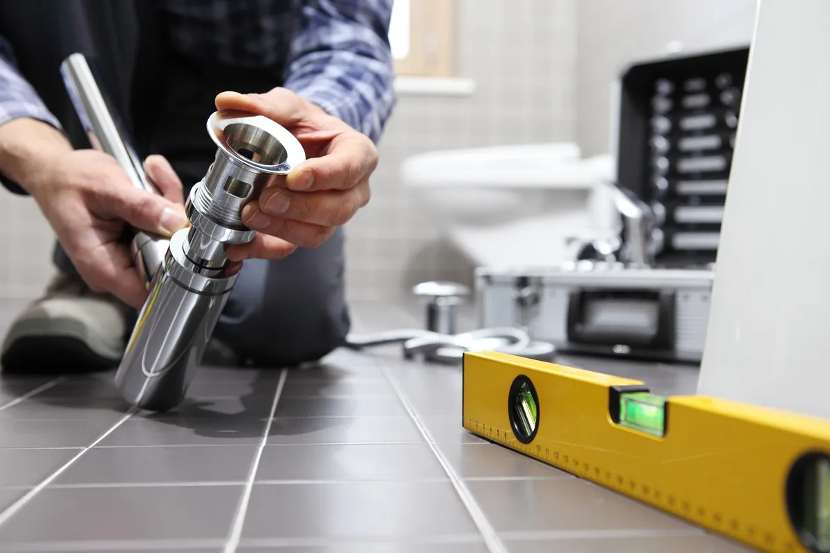 Plombier en train d'installer un siphon dans une salle de bains pour un nouveau réseau de plomberie.